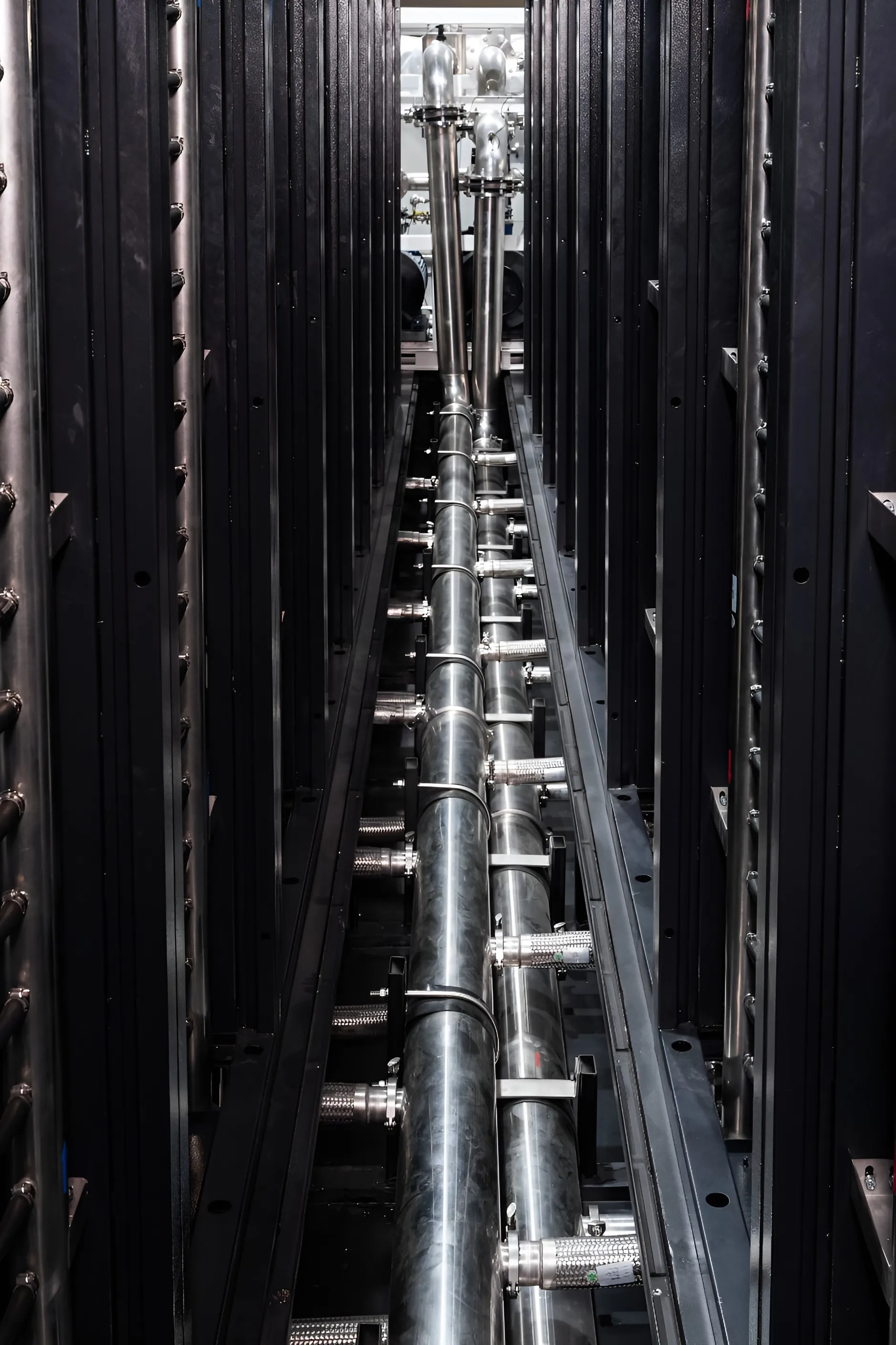 Stainless supply and return piping running between two rows of racks.